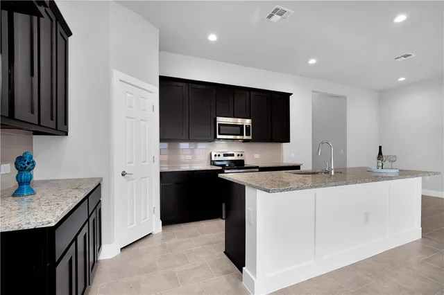 a kitchen with stainless steel appliances granite countertop a sink a stove and a refrigerator