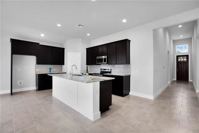 a kitchen with stainless steel appliances kitchen island granite countertop a refrigerator and a stove top oven