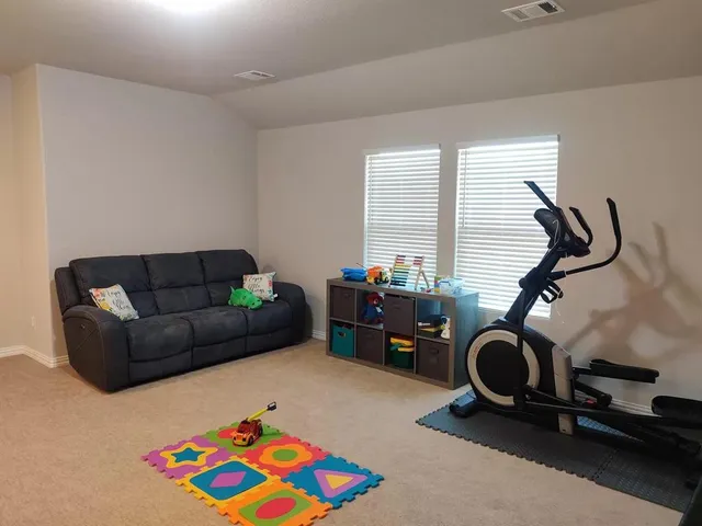 a living room with furniture gym equipment and a window