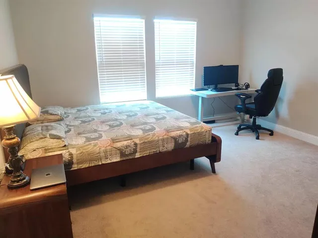 a bedroom with a bed chair and computer on the desk