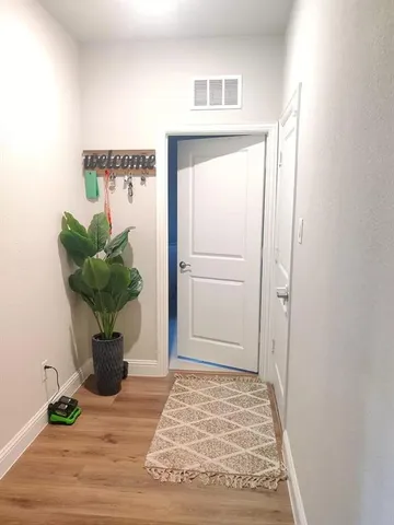 a view of a hallway with wooden floor and a potted plant