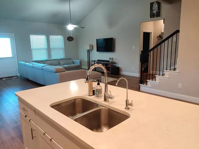 a kitchen with a sink and a stove top oven with wooden floor