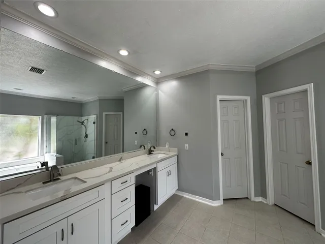 a spacious bathroom with a double vanity sink a large mirror and a shower