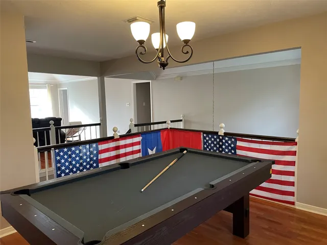 a room with pool table and wooden floor