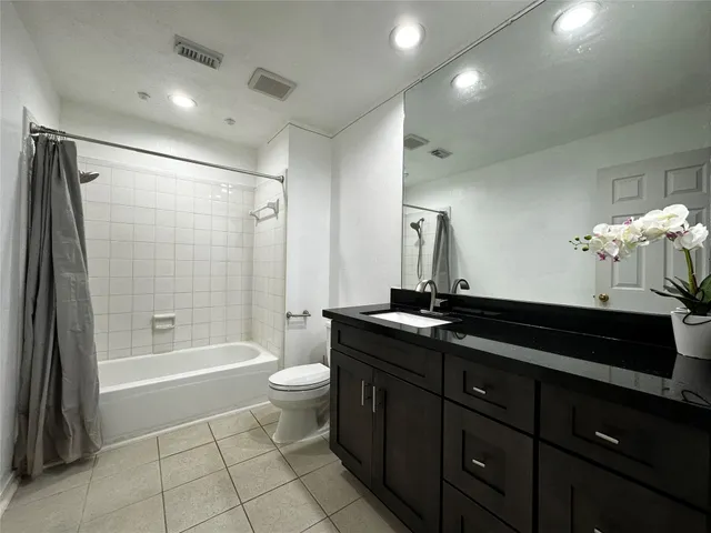 a spacious bathroom with a granite countertop sink a toilet a mirror a bathtub and shower