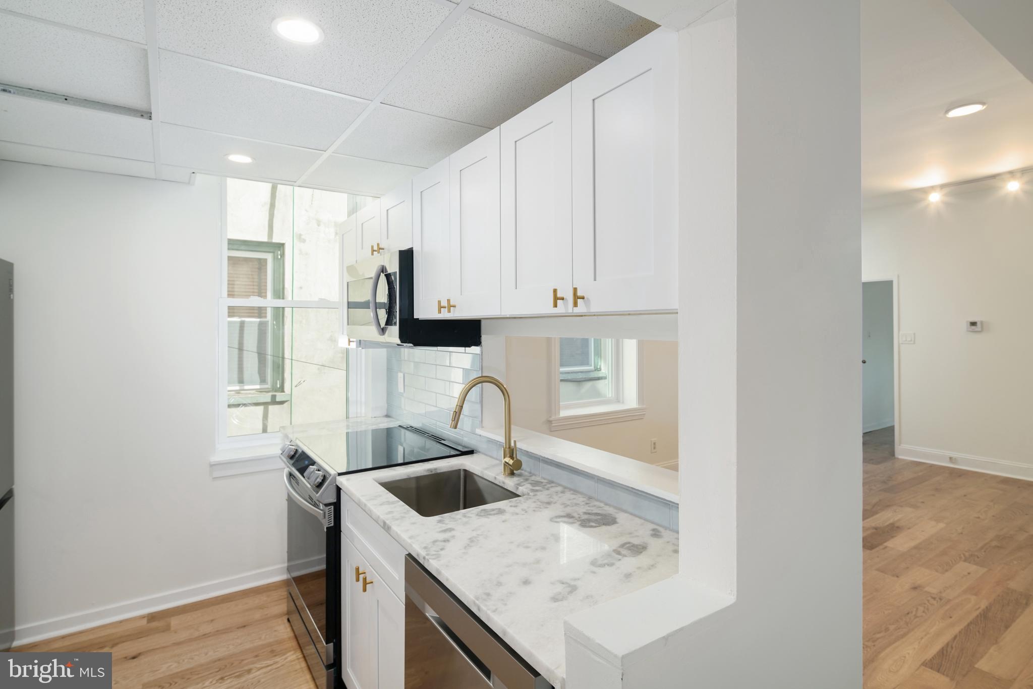 a kitchen with granite countertop a sink a stove and refrigerator
