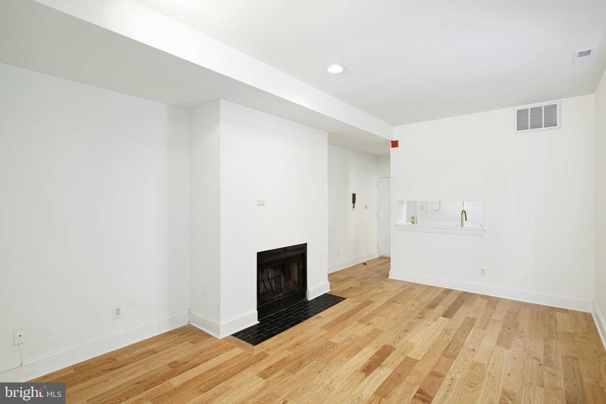 1716 Wallace Street, Unit 202 Philadelphia, PA 19130 - Photo 5 of 12 a view of empty room with wooden floor and fireplace