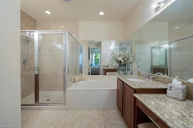 a bathroom with a granite countertop sink a mirror a bathtub and shower