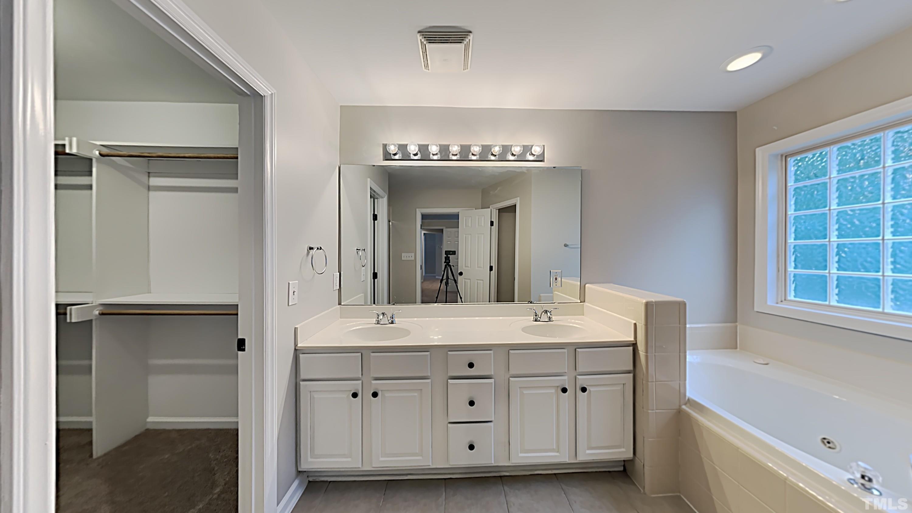 5020 Amberfield Way Raleigh, NC 27604 - Photo 14 of 24 a spacious bathroom with a double vanity sink a mirror and a bathtub