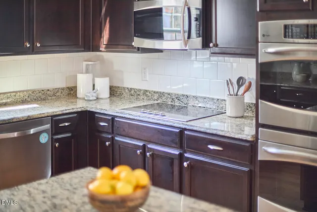 a kitchen with stainless steel appliances a dining table chairs refrigerator and sink