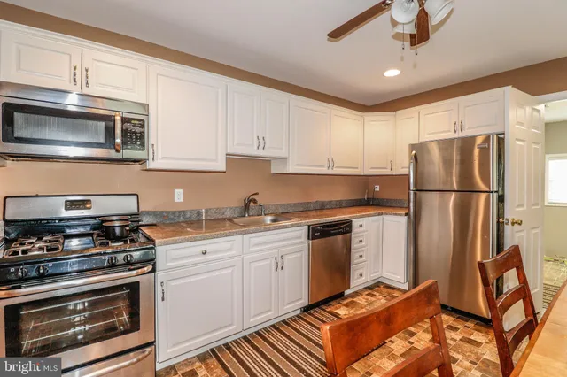 a kitchen with granite countertop a refrigerator stove and white cabinets