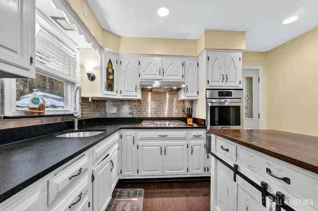 a kitchen with stainless steel appliances granite countertop a sink stove and cabinets