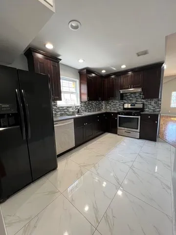 a large kitchen with stainless steel appliances granite countertop a refrigerator and a sink