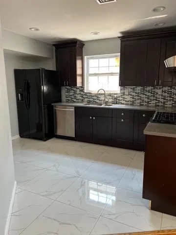 a large kitchen with granite countertop a stove a refrigerator and a sink