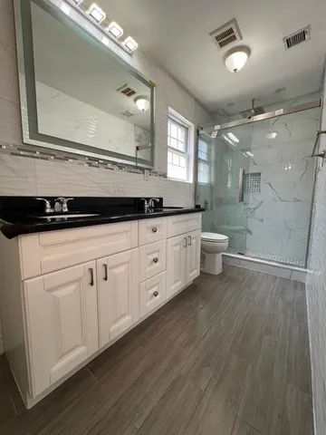a spacious bathroom with a granite countertop sink toilet a mirror and shower