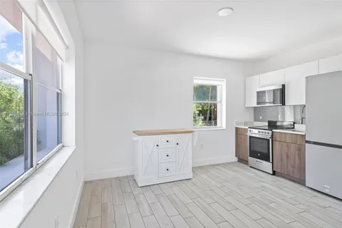 a kitchen with a refrigerator wooden floor and a large window