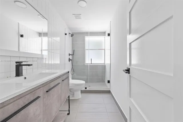 a bathroom with a shower sink vanity and toilet
