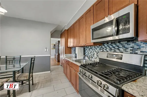 a kitchen with a stove a microwave and chairs