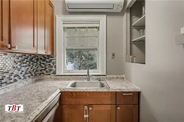 a bathroom with a granite countertop sink a window and a shower