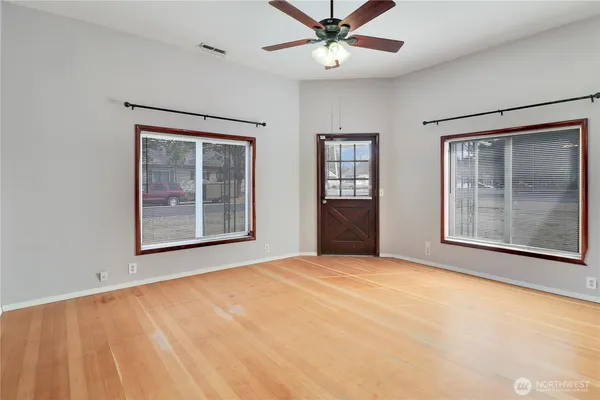 a view of an empty room with chandelier fan and a window