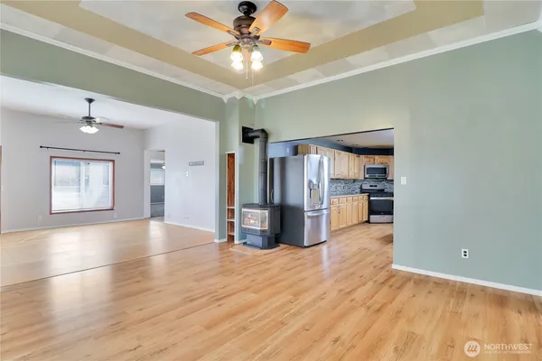 a view of a kitchen with a stove cabinet a ceiling fan and wooden floor