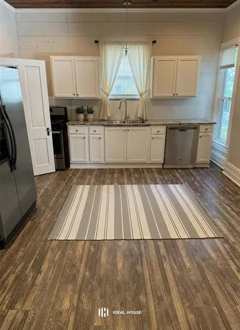 a kitchen with wooden floors sink and cabinets