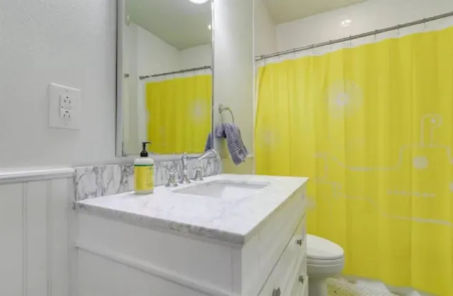 a bathroom with a granite countertop sink and a toilet