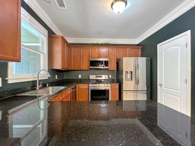 1232 Harris Commons Place, Unit 15 Roswell, GA 30076 - Photo 12 of 36 a kitchen with stainless steel appliances granite countertop a stove a sink and a refrigerator