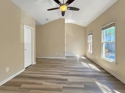 a view of an empty room with window and wooden floor