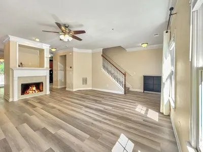 a view of a livingroom with a fireplace a ceiling fan and front door