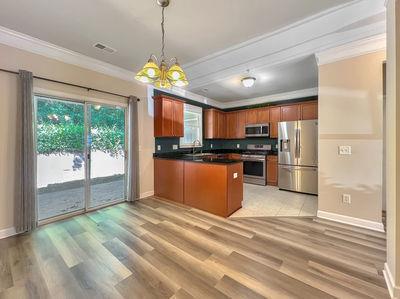 1232 Harris Commons Place, Unit 15 Roswell, GA 30076 - Photo 9 of 36 a open kitchen with stainless steel appliances granite countertop a refrigerator a stove top oven a sink and dishwasher with wooden floor