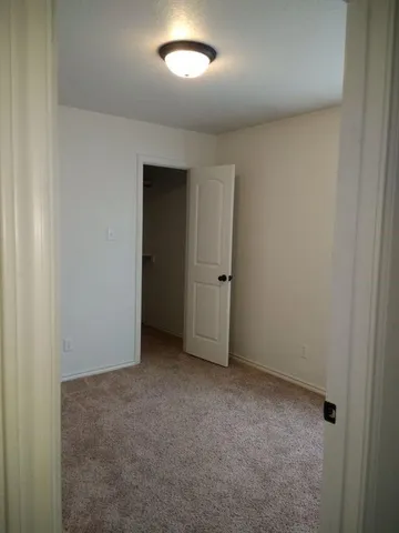 an empty room with a fan & a window