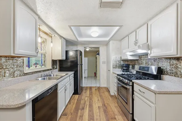 a kitchen with stainless steel appliances granite countertop a sink stove cabinets and refrigerator