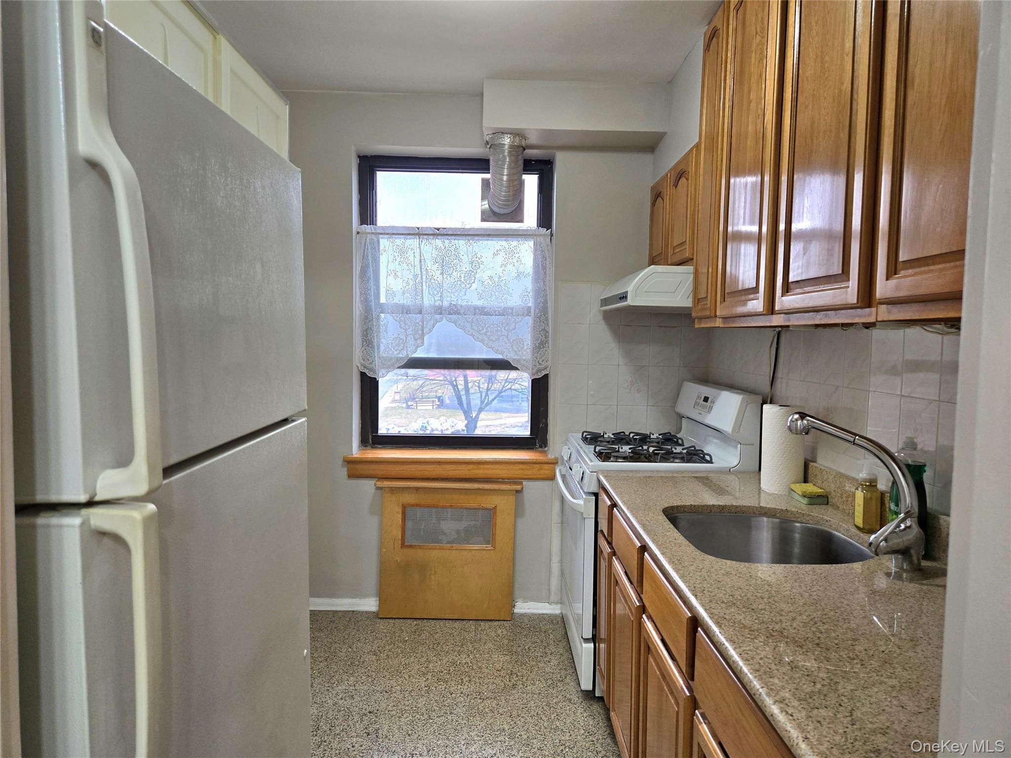 138-18 28th Road, Unit 2F Queens, NY 11354 - Photo 12 of 13 a kitchen with stainless steel appliances granite countertop a refrigerator a sink and a window