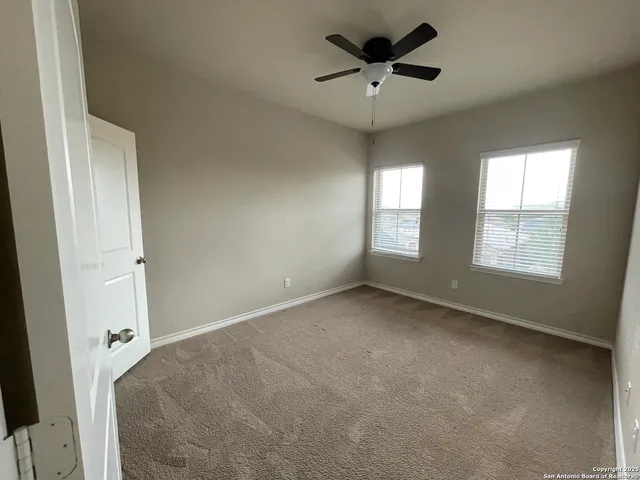 an empty room with windows and ceiling fan