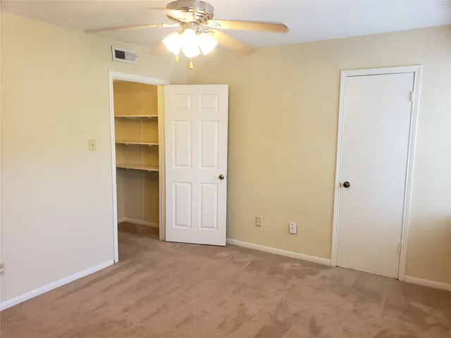 an empty room with closet and a chandelier fan