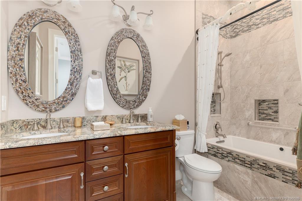 2690 Northwest Collins Cove Road Stuart, FL 34994 - Photo 53 of 100 a bathroom with double vanity sinks a toilet a mirror and a tub