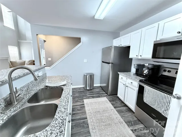 a kitchen with stainless steel appliances granite countertop a sink a stove and refrigerator