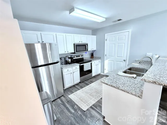 a kitchen with granite countertop a refrigerator a sink a stove a microwave a counter space and cabinets