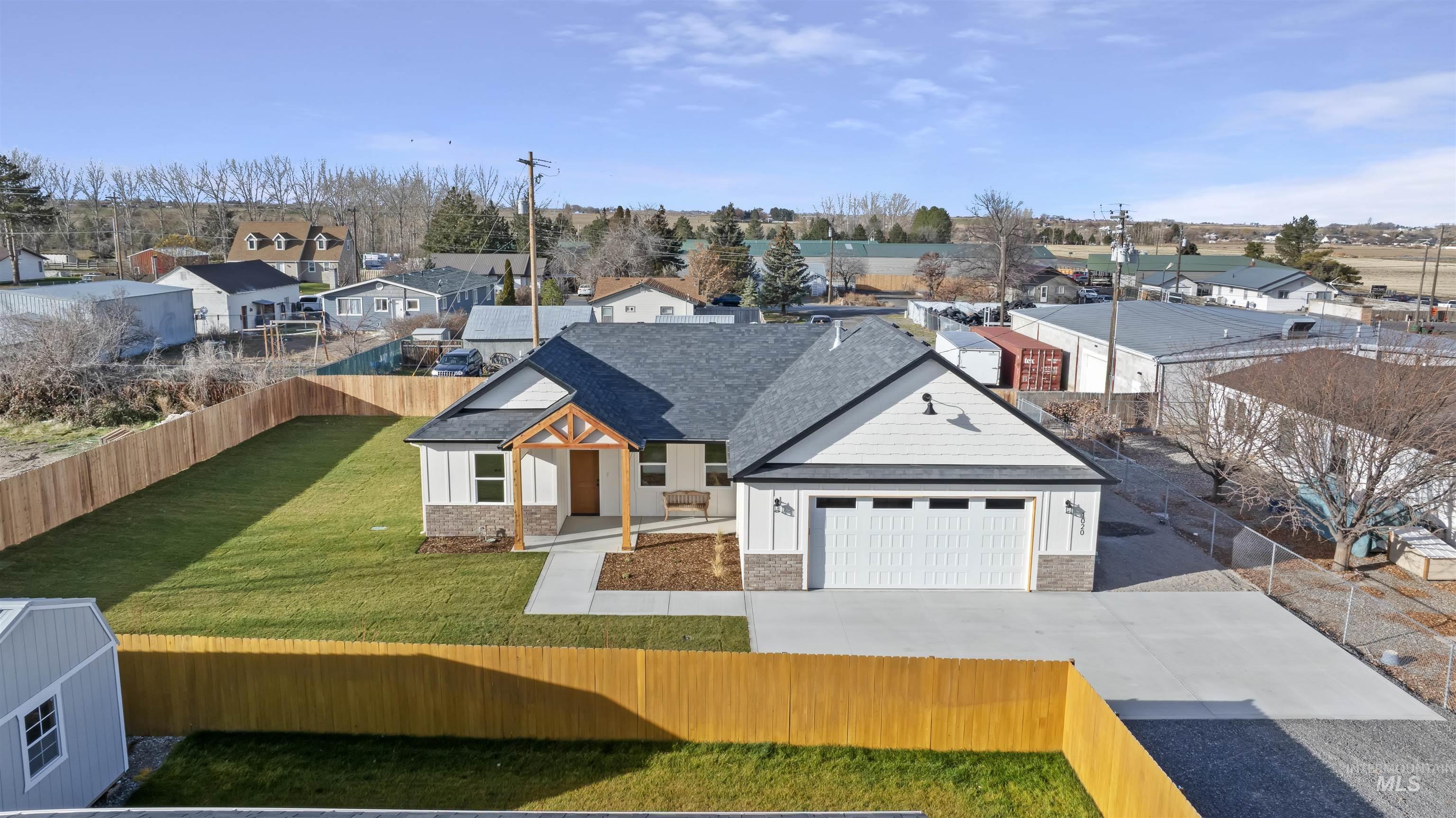 View of front of home with stone siding, a residential view, a shingled roof, concrete driveway, and board and batten siding