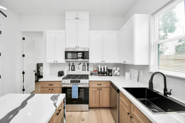 a kitchen with stainless steel appliances a white stove top oven sink and cabinets