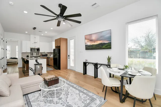 a living room with furniture kitchen view and a large window