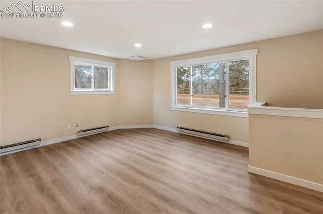 an empty room with wooden floor and windows