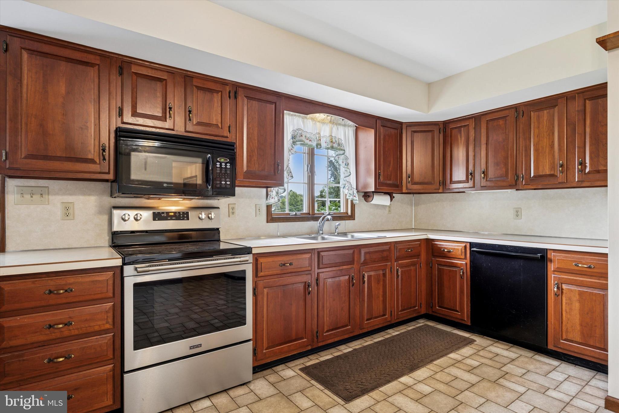 1690 Kumry Road Quakertown, PA 18951 - Photo 10 of 34 a kitchen with granite countertop wooden cabinets stainless steel appliances and a window