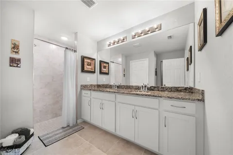 a bathroom with a granite countertop sink a mirror and a shower
