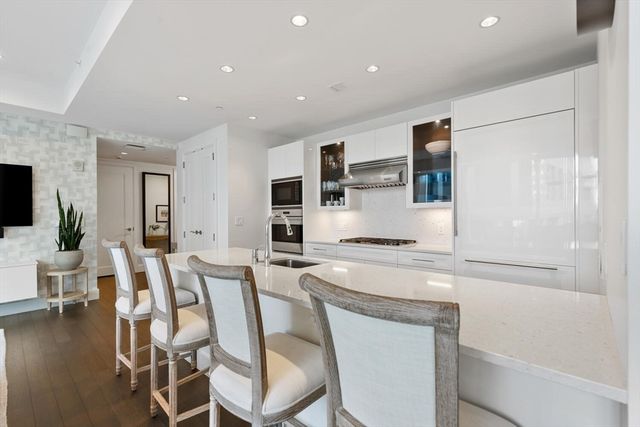 a kitchen with stainless steel appliances a stove a sink white cabinets and a refrigerator