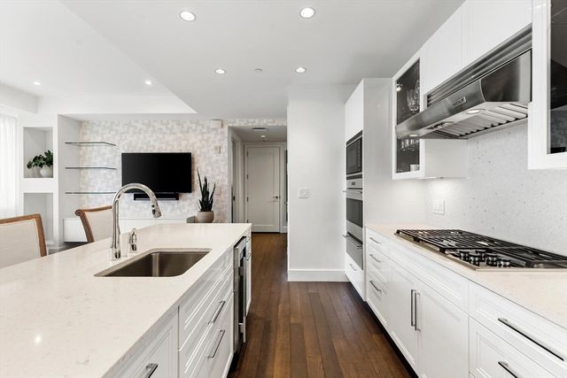 a kitchen with sink a microwave and stove top oven with wooden floor