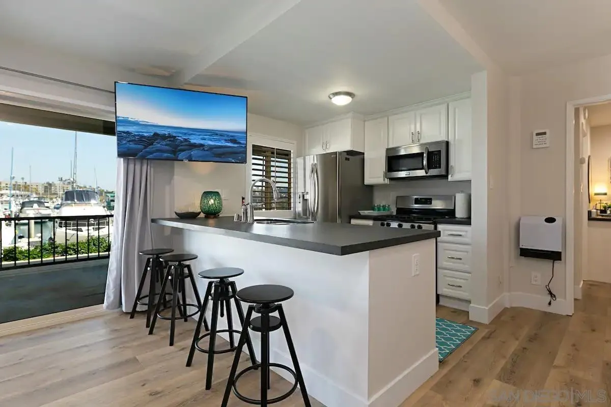 1202 North Pacific Street, Unit 106B Oceanside, CA 92054 - Photo 2 of 17 a kitchen with stainless steel appliances kitchen island granite countertop a refrigerator a stove a sink and white cabinets with wooden floor