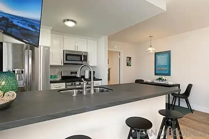 1202 North Pacific Street, Unit 106B Oceanside, CA 92054 - Photo 4 of 17 a kitchen with a table chairs and refrigerator