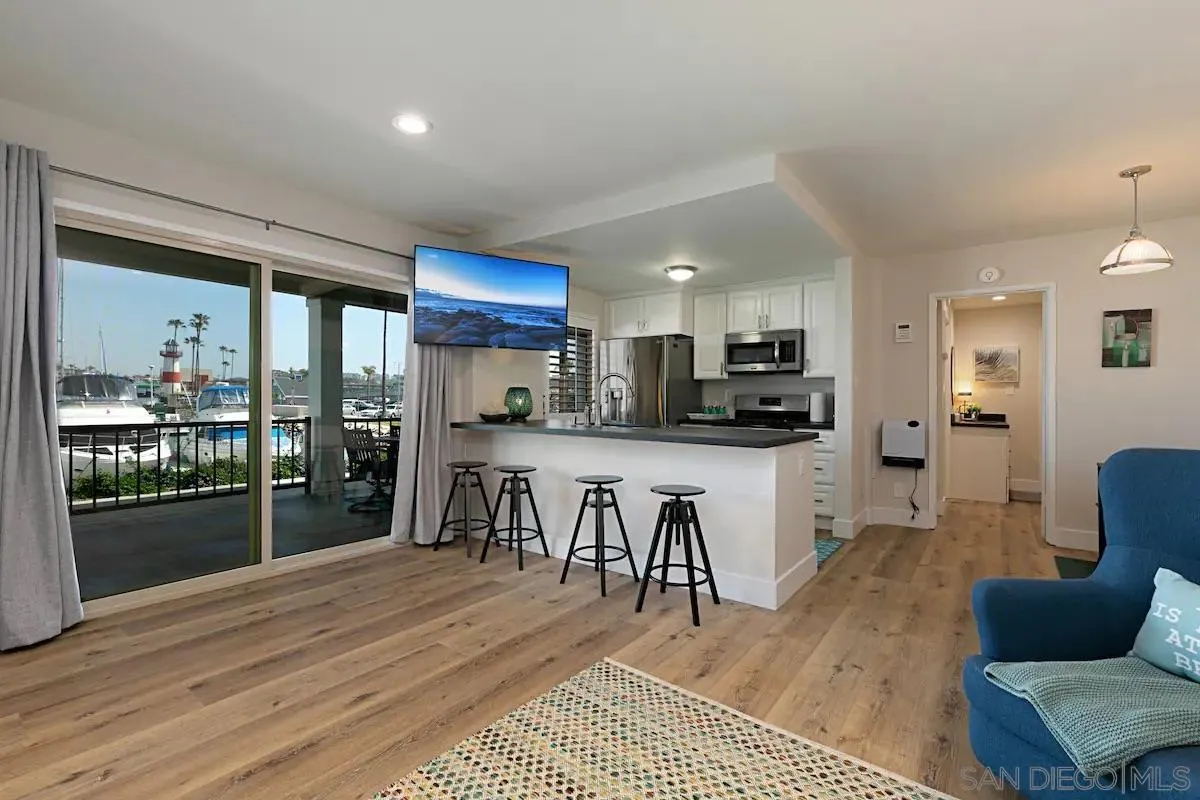 1202 North Pacific Street, Unit 106B Oceanside, CA 92054 - Photo 7 of 17 a kitchen with stainless steel appliances kitchen island granite countertop a refrigerator a stove top oven a sink with island and chairs